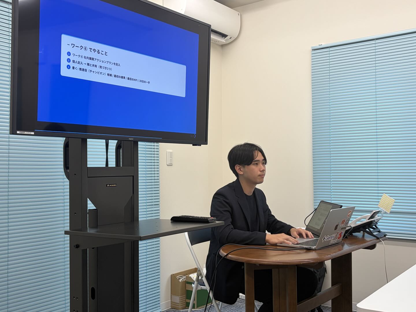 研修講師がスライドを投影しながらワークの進め方を説明している様子