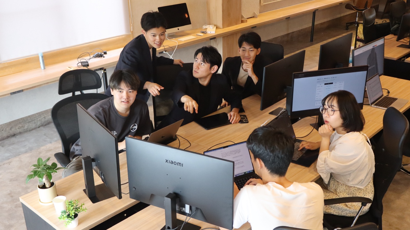 百万遍オフィスで一台のモニターを囲んで打ち合わせをするメンバー